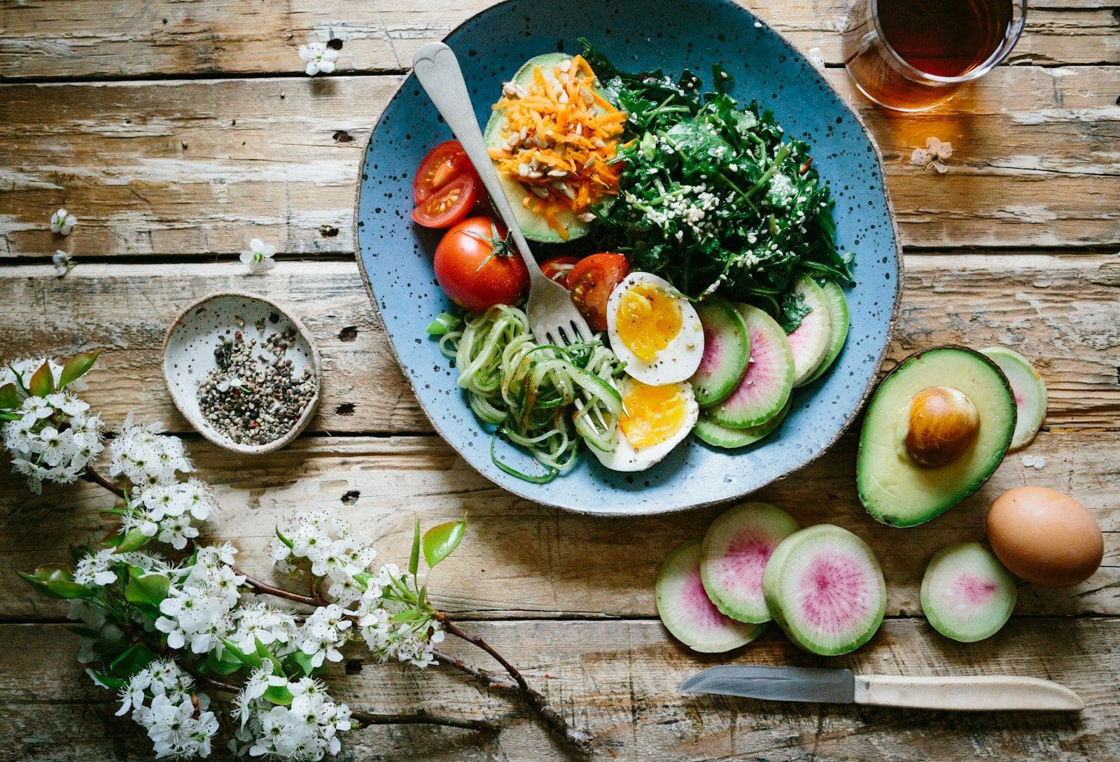 Bowl con huevo, aguacate y verduras sobre madera